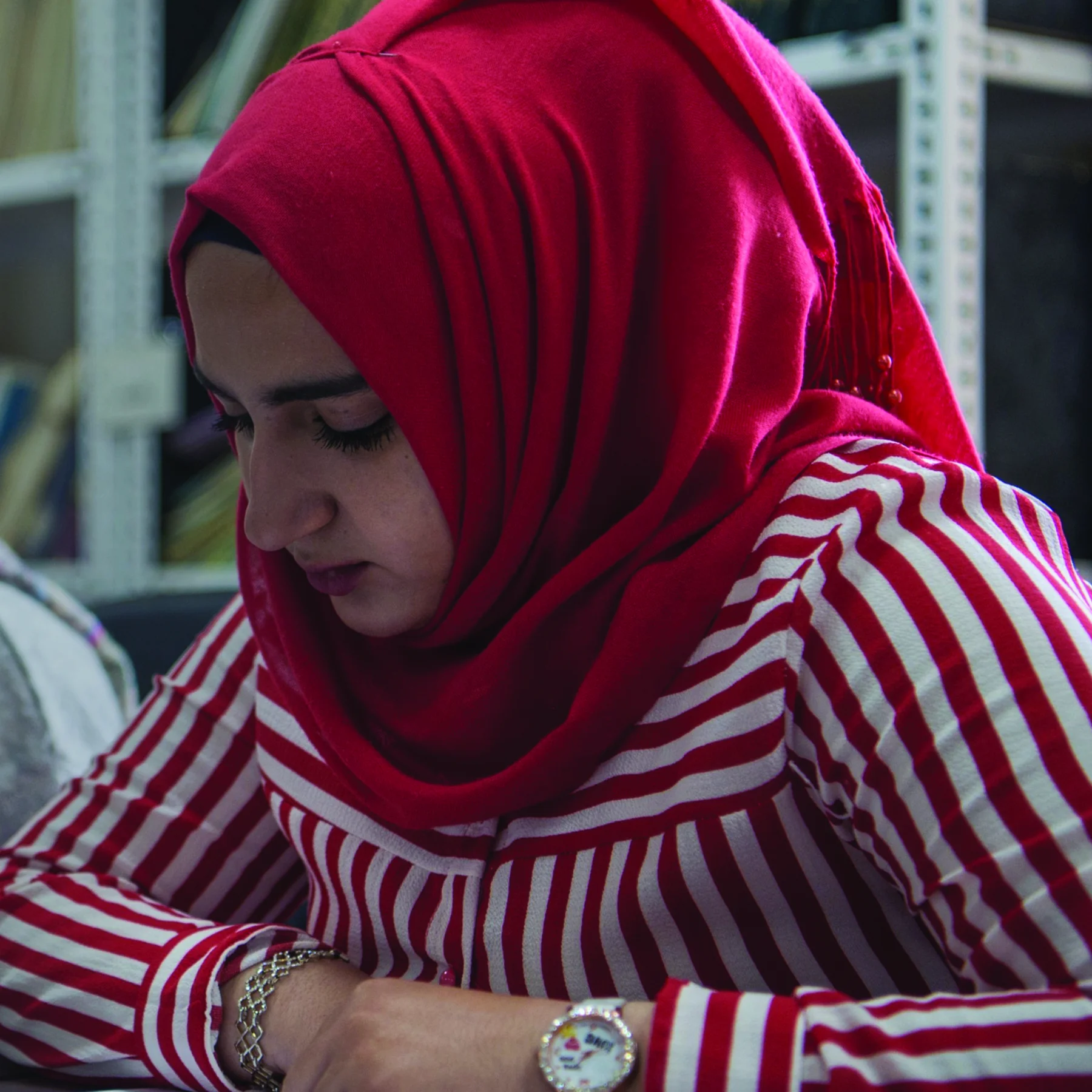 A woman in a red headscarf reading inside the library